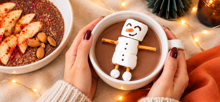 Kobiece dłonie trzymają kubek kakao z bałwankiem z marshmallow